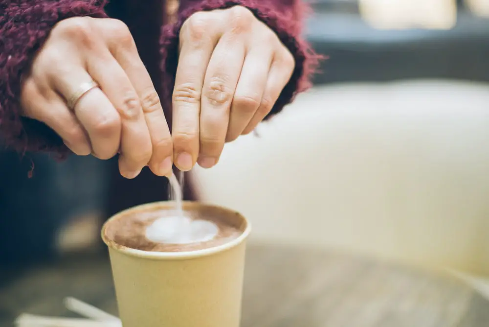Woman hands pouring sugar latte cup