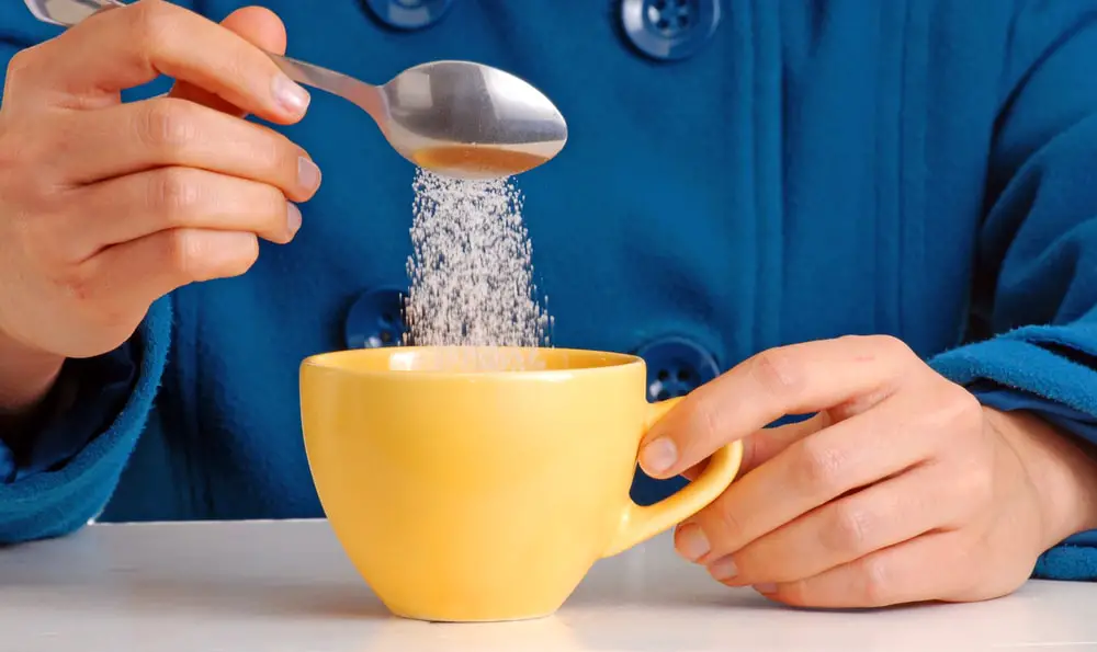 woman-pouring-sugar-on-coffee-cup