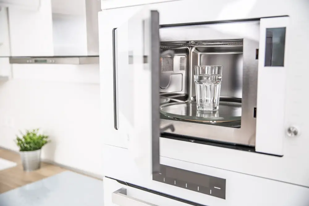 Built-in microwave oven in the kitchen with a cup of pure water