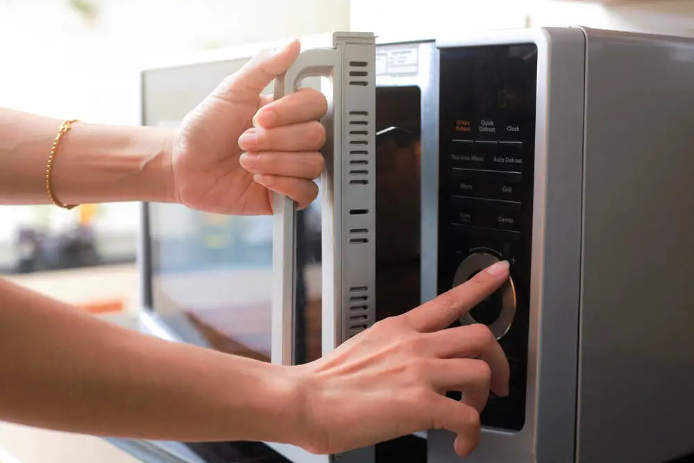 womans-hands-closing-microwave-oven-door