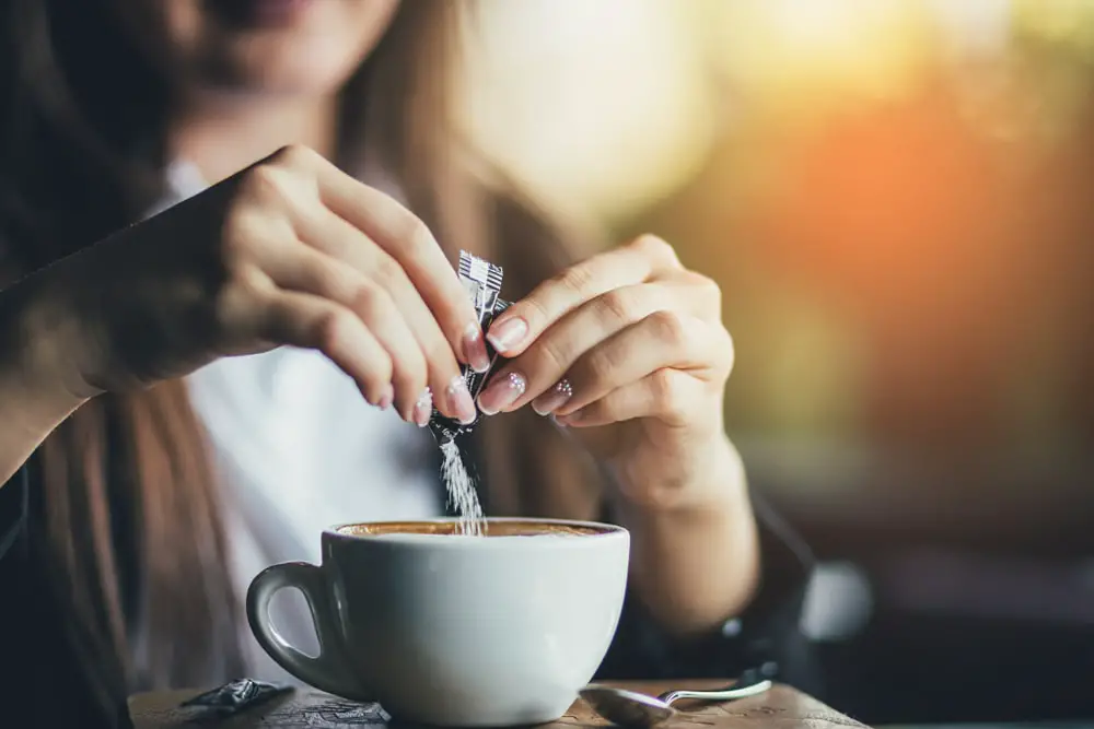 female-hand-pours-sugar-into-coffee